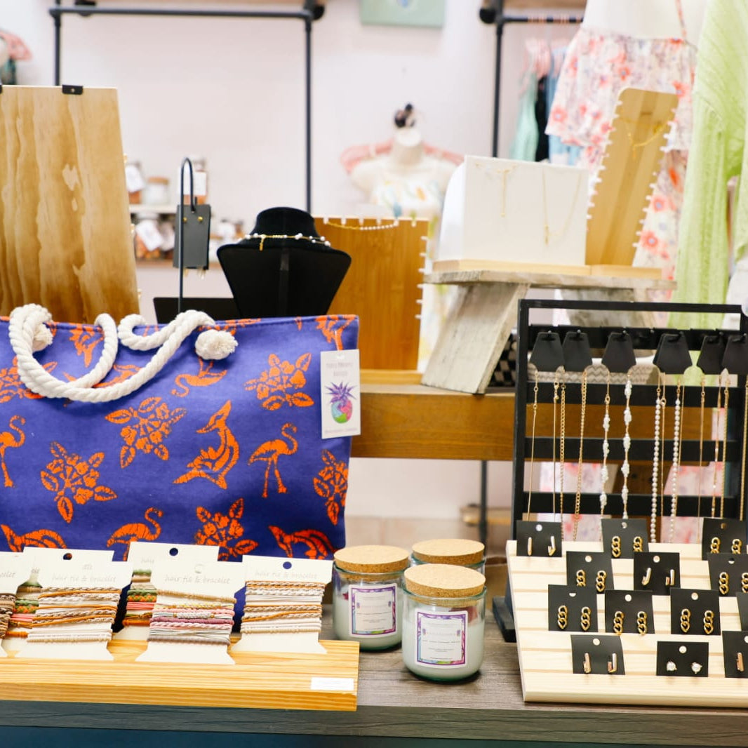 Display of various items including a blue bag with orange designs, candles, and a decorative item in a store setting.