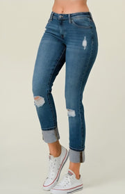 Blue distressed jeans worn by a person on a plain background